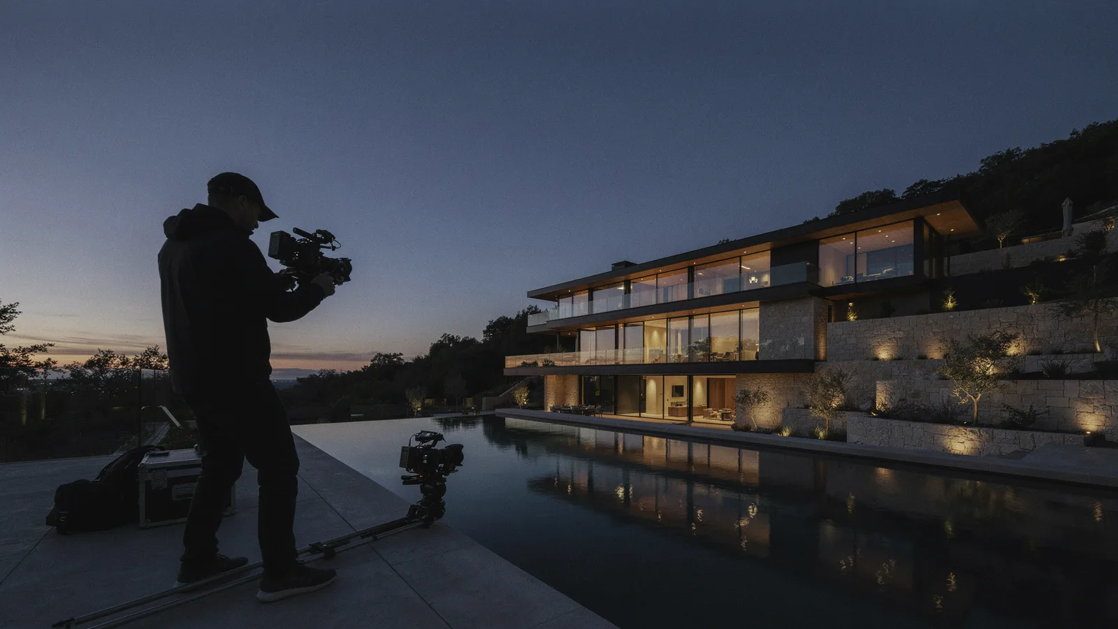 Luxury real estate video shoot at dusk with a videographer filming a modern hillside home